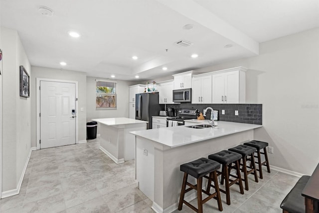 kitchen with kitchen peninsula, tasteful backsplash, a breakfast bar, stainless steel appliances, and sink