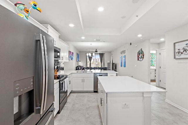 kitchen with kitchen peninsula, appliances with stainless steel finishes, a kitchen island, ceiling fan, and white cabinetry