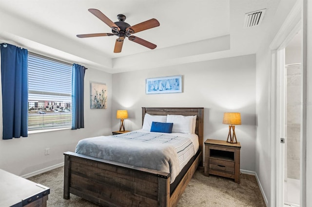 bedroom featuring light carpet, a tray ceiling, and ceiling fan