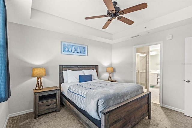 carpeted bedroom with ceiling fan, a raised ceiling, and connected bathroom