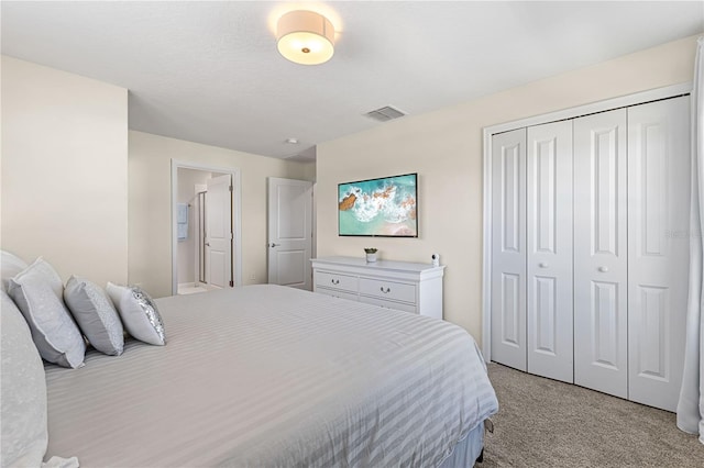 bedroom with light colored carpet, ensuite bath, and a closet