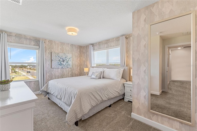 carpeted bedroom featuring a textured ceiling and multiple windows