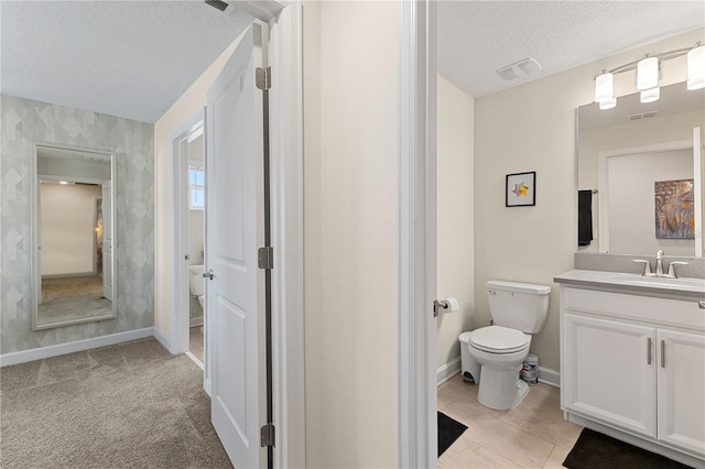 bathroom featuring vanity, a textured ceiling, toilet, and tile patterned flooring