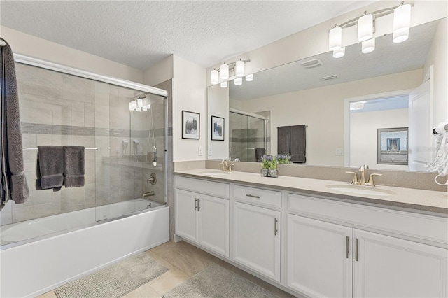 bathroom featuring shower / bath combination with glass door, vanity, a textured ceiling, and tile patterned flooring