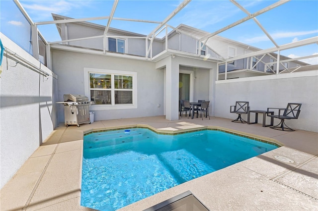 view of swimming pool featuring glass enclosure, a patio, and grilling area