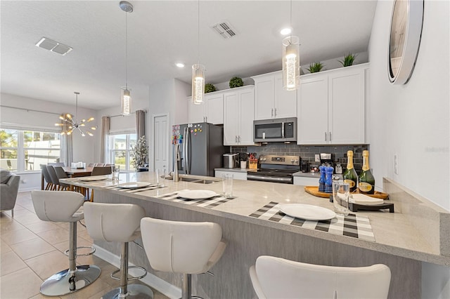 kitchen featuring appliances with stainless steel finishes, pendant lighting, tasteful backsplash, and a breakfast bar area