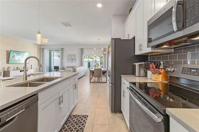 kitchen with white cabinets, sink, appliances with stainless steel finishes, decorative light fixtures, and light tile patterned flooring