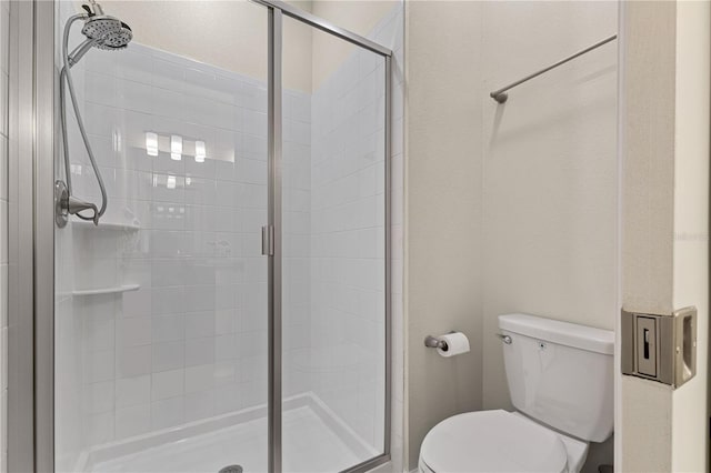 bathroom featuring toilet and a shower with door