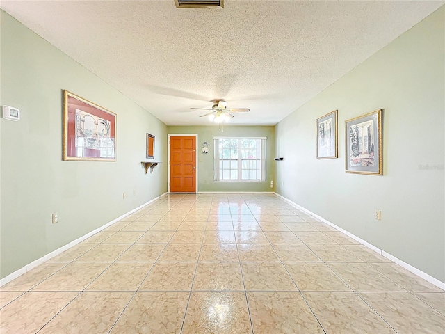 spare room with a textured ceiling, ceiling fan, and light tile patterned flooring