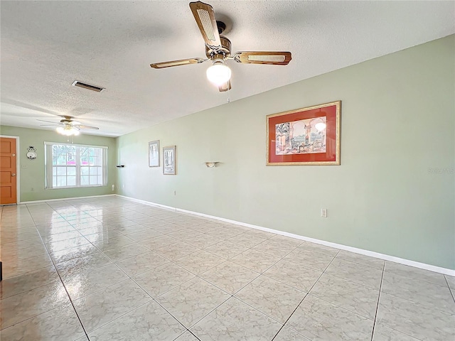 spare room with ceiling fan, light tile patterned floors, and a textured ceiling