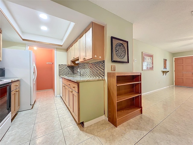 kitchen featuring stainless steel range, sink, a raised ceiling, decorative backsplash, and light tile patterned floors