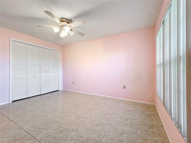 unfurnished bedroom with ceiling fan, a textured ceiling, and a closet