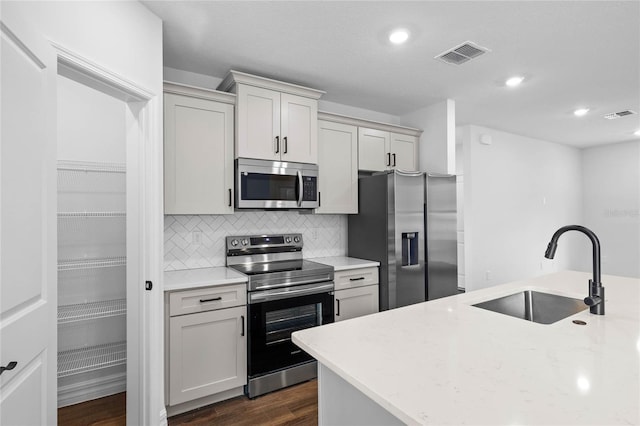 kitchen with backsplash, sink, dark hardwood / wood-style floors, light stone countertops, and appliances with stainless steel finishes