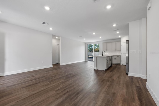 kitchen featuring stainless steel fridge, an island with sink, and dark hardwood / wood-style floors