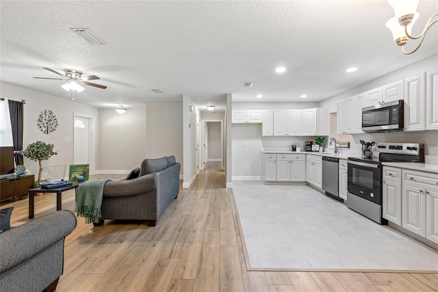 kitchen with white cabinetry, light wood-type flooring, a textured ceiling, and appliances with stainless steel finishes