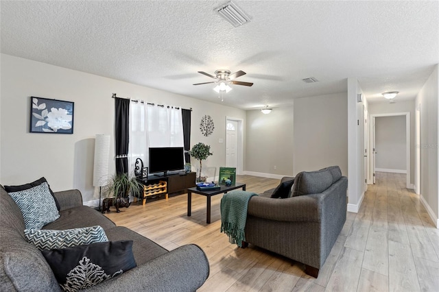 living room with hardwood / wood-style flooring, ceiling fan, and a textured ceiling