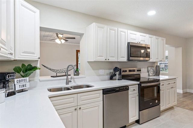 kitchen with light wood-type flooring, stainless steel appliances, ceiling fan, sink, and white cabinets