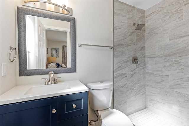 bathroom with tiled shower, vanity, and toilet