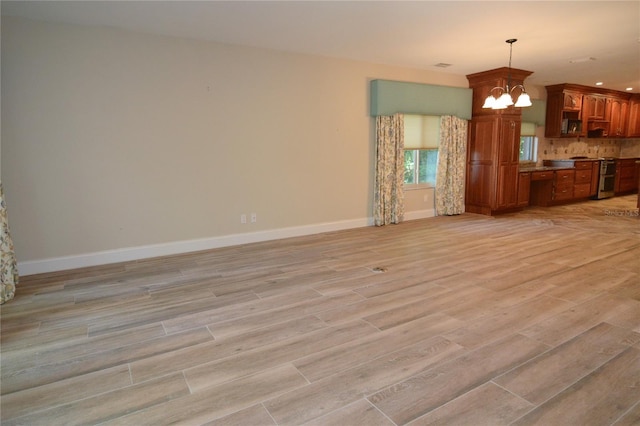 unfurnished living room featuring light hardwood / wood-style flooring and a notable chandelier