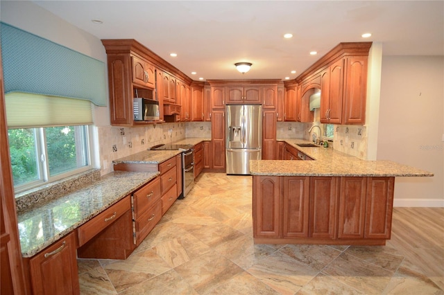 kitchen featuring kitchen peninsula, decorative backsplash, light stone counters, stainless steel appliances, and sink