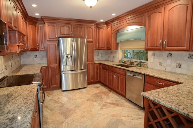 kitchen with light stone countertops, sink, appliances with stainless steel finishes, and tasteful backsplash