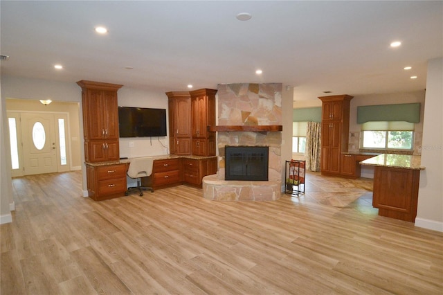 unfurnished living room with a fireplace, built in desk, and light hardwood / wood-style flooring