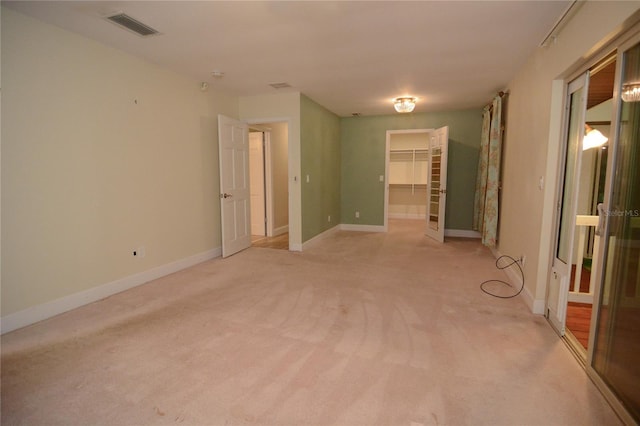 unfurnished bedroom featuring a spacious closet, a closet, and light carpet