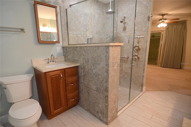 bathroom with walk in shower, ceiling fan, vanity, and toilet