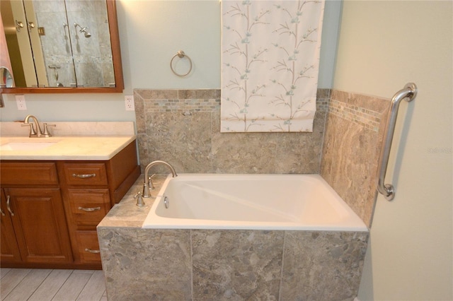 bathroom with vanity and tiled bath