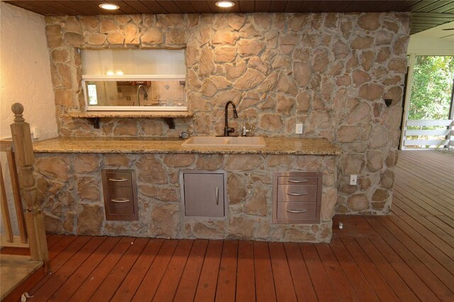 bar featuring hardwood / wood-style floors, light stone countertops, and sink