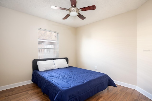 bedroom with a textured ceiling, ceiling fan, and dark wood-type flooring