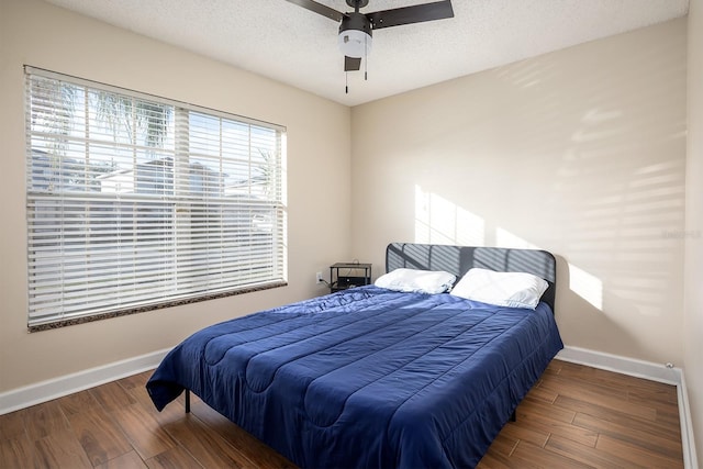 bedroom with ceiling fan, dark hardwood / wood-style flooring, and a textured ceiling