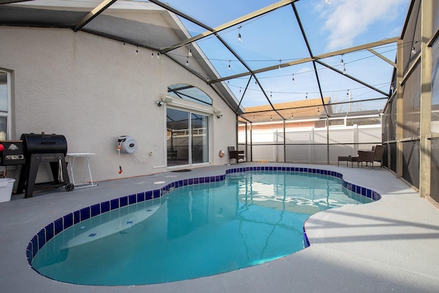 view of swimming pool with a patio, glass enclosure, and a grill