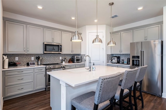 kitchen featuring pendant lighting, backsplash, sink, appliances with stainless steel finishes, and dark hardwood / wood-style flooring