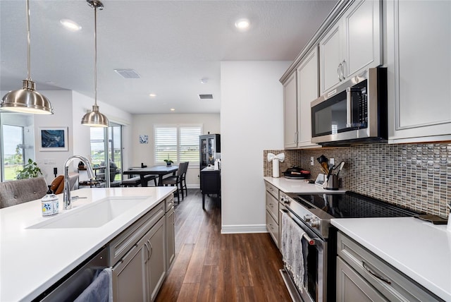 kitchen featuring appliances with stainless steel finishes, dark wood-type flooring, sink, pendant lighting, and gray cabinets