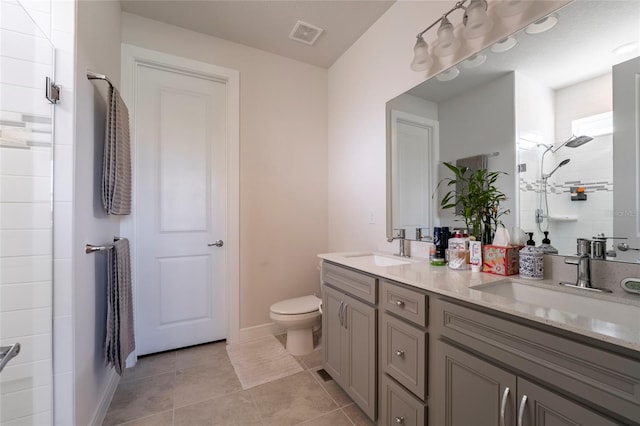 bathroom featuring tile patterned floors, toilet, vanity, and tiled shower