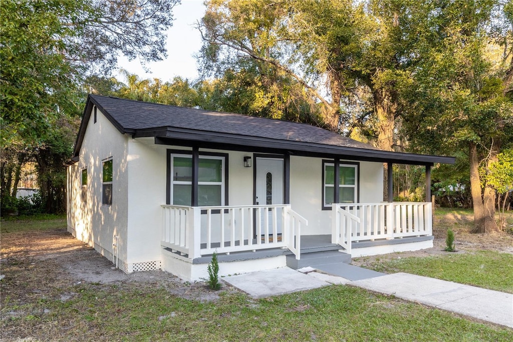 ranch-style home featuring covered porch and a front lawn