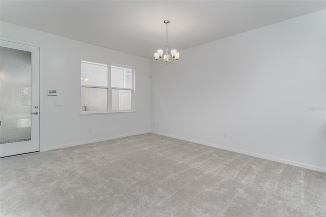 unfurnished room featuring a chandelier and light carpet