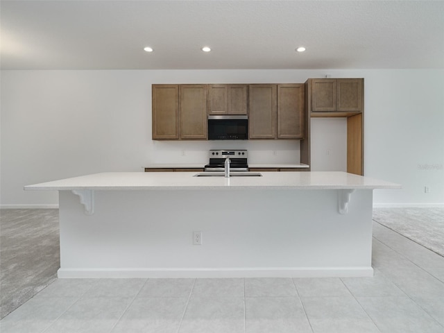 kitchen with a large island with sink, stainless steel appliances, light colored carpet, and sink