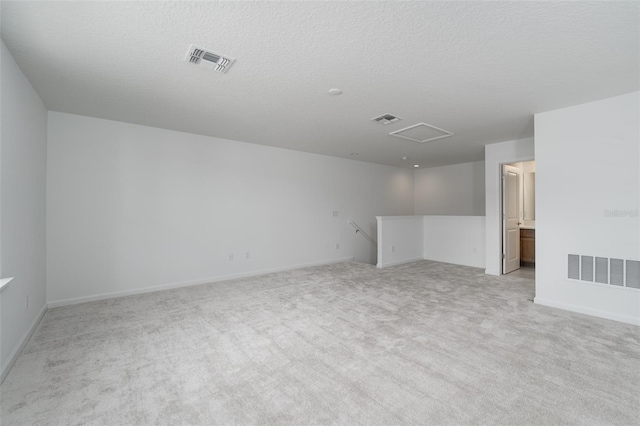 spare room with light colored carpet and a textured ceiling