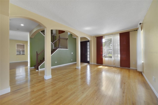 unfurnished room with light wood-type flooring and a textured ceiling