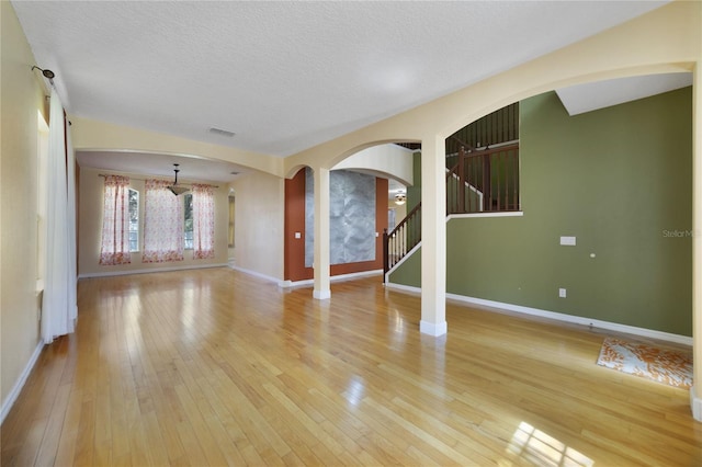 empty room with a textured ceiling and light hardwood / wood-style floors