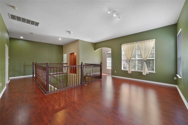 empty room featuring a textured ceiling and dark hardwood / wood-style floors