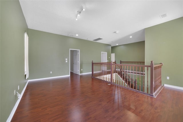 empty room featuring a textured ceiling, dark hardwood / wood-style floors, and track lighting