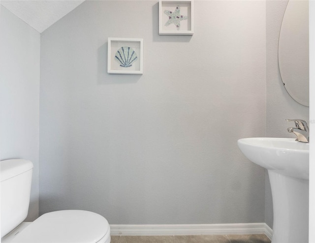 bathroom with tile patterned floors, toilet, lofted ceiling, and sink