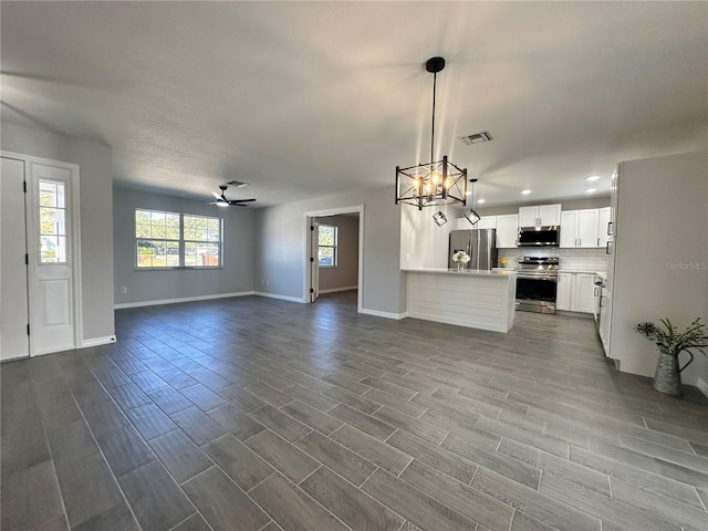 kitchen with white cabinets, hardwood / wood-style flooring, pendant lighting, and appliances with stainless steel finishes