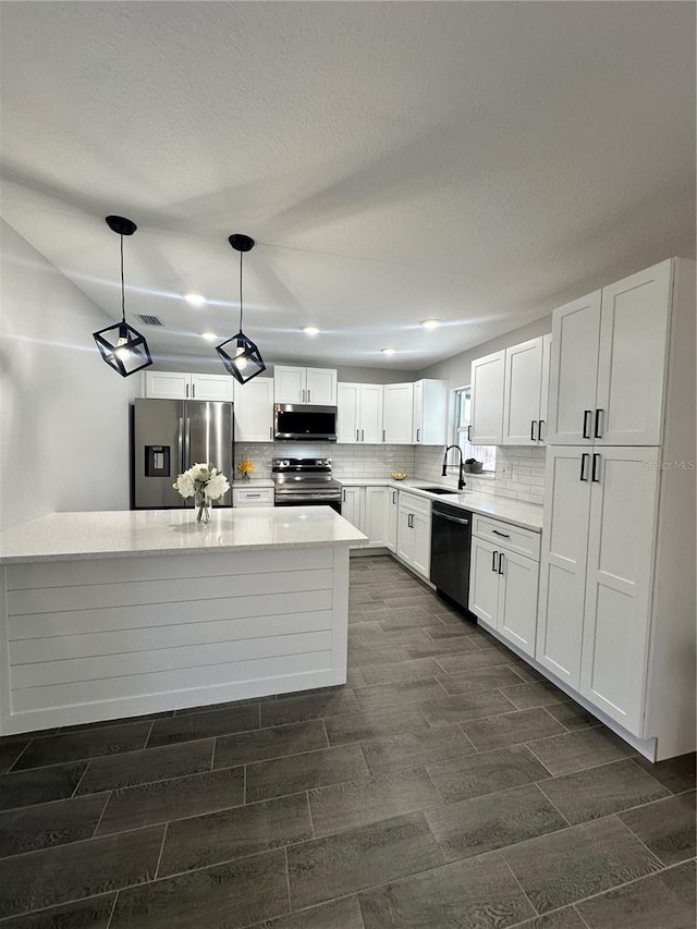 kitchen with sink, hanging light fixtures, tasteful backsplash, white cabinets, and appliances with stainless steel finishes