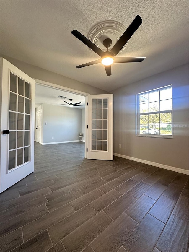 spare room with a textured ceiling, ceiling fan, french doors, and dark hardwood / wood-style floors