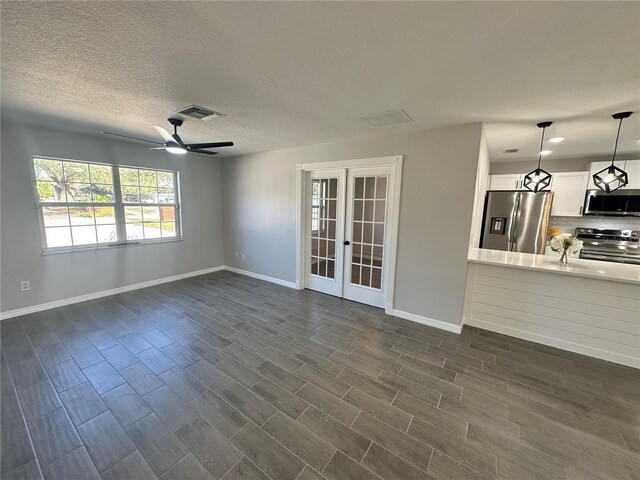 unfurnished living room with french doors, a textured ceiling, ceiling fan, and dark wood-type flooring