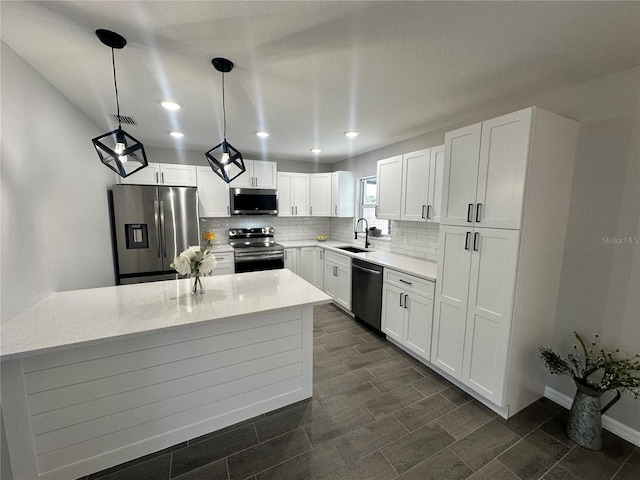 kitchen with sink, hanging light fixtures, light stone counters, white cabinetry, and stainless steel appliances